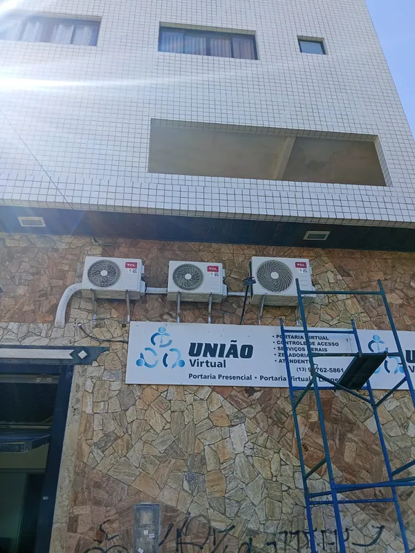 Três unidades externas de ar-condicionado instaladas na fachada de um prédio